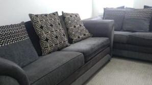 A grey sofa with patterned cushions and a grey carpet. - Gourock Blissful Apartment With 3 Bedrooms (Gourock)