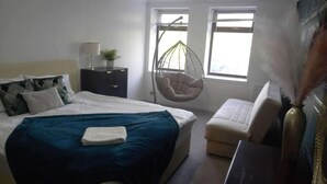 A bedroom with a bed, a hanging chair, a bedside table, and a window. - Gourock Blissful Apartment With 3 Bedrooms (Gourock)