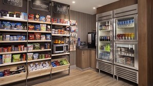 Un rayon dédié aux en-cas, avec des étagères remplies de divers produits emballés, et un présentoir réfrigéré contenant des boissons.