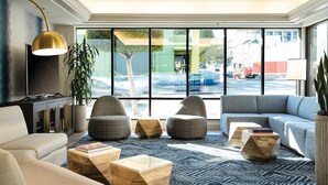Un salon moderne avec un canapé, des fauteuils et des tables basses en bois.