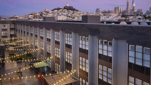 Une terrasse sur le toit, agrémentée de guirlandes lumineuses et de mobilier d’extérieur, offrant une vue panoramique sur la ville et ses bâtiments modernes.