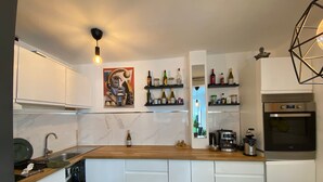 Una cocina moderna con armarios blancos, encimera de madera, horno integrado y cafetera.