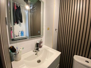 A bathroom with a white sink, a mirror, and striped wallpaper. - Beautiful studio near the Sagrada familia and the beach (Barcelona)