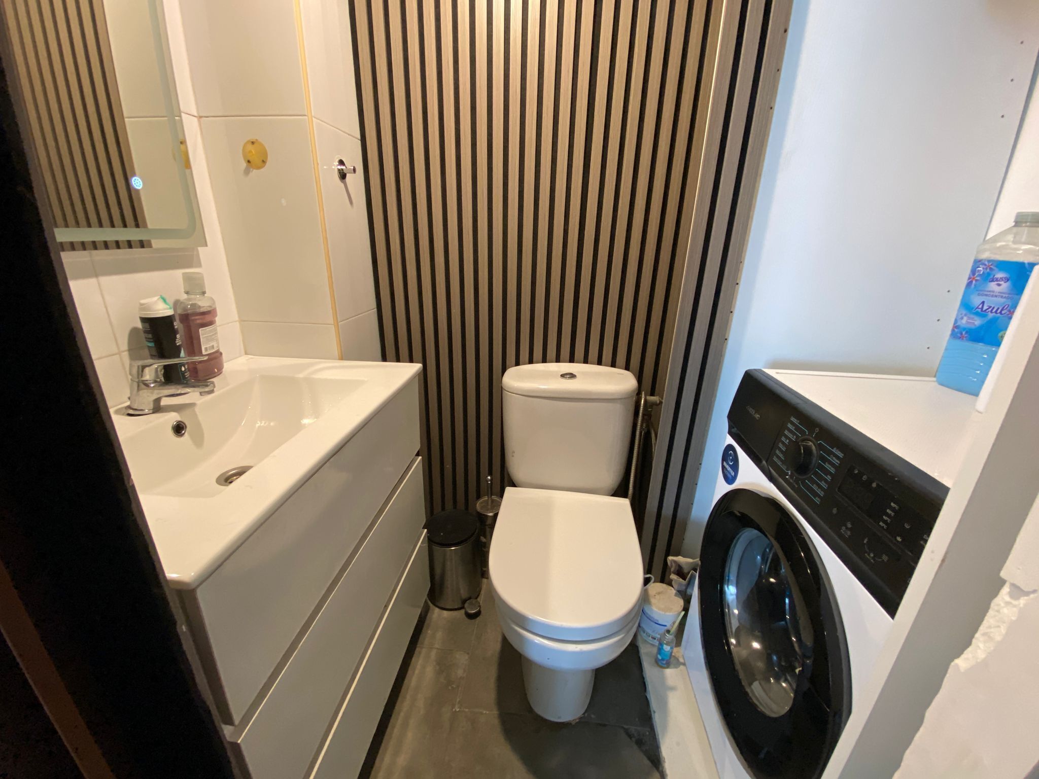 Un baño pequeño con bañera blanca, inodoro y lavadora.
