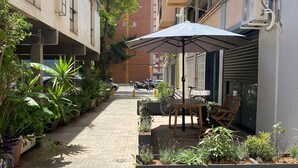Un estrecho callejón con macetas y mesas al aire libre.