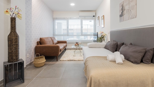 A modern bedroom with a sofa, a bed, a coffee table, and a decorative vase.
