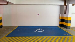 Un parking avec une place de stationnement réservée aux personnes handicapées, marquée en bleu et signalée par le symbole d’un fauteuil roulant.