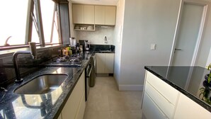 Une cuisine de taille réduite, équipée de deux éviers, d’une cuisinière et d’un plan de travail sur lequel sont disposés divers objets.
