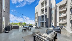 A modern outdoor patio area with seating, tables, and string lights.