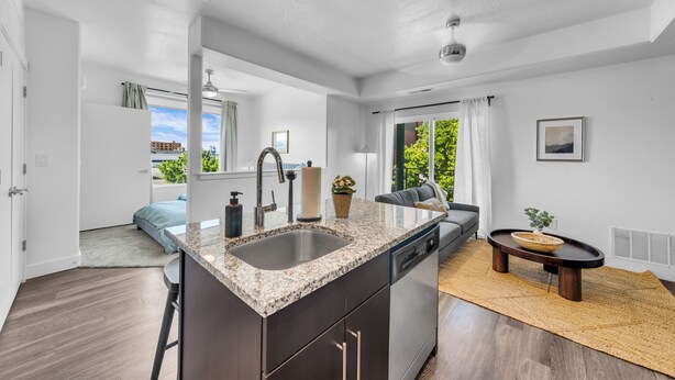 A modern kitchen with a granite countertop, stainless steel appliances, and a large window.