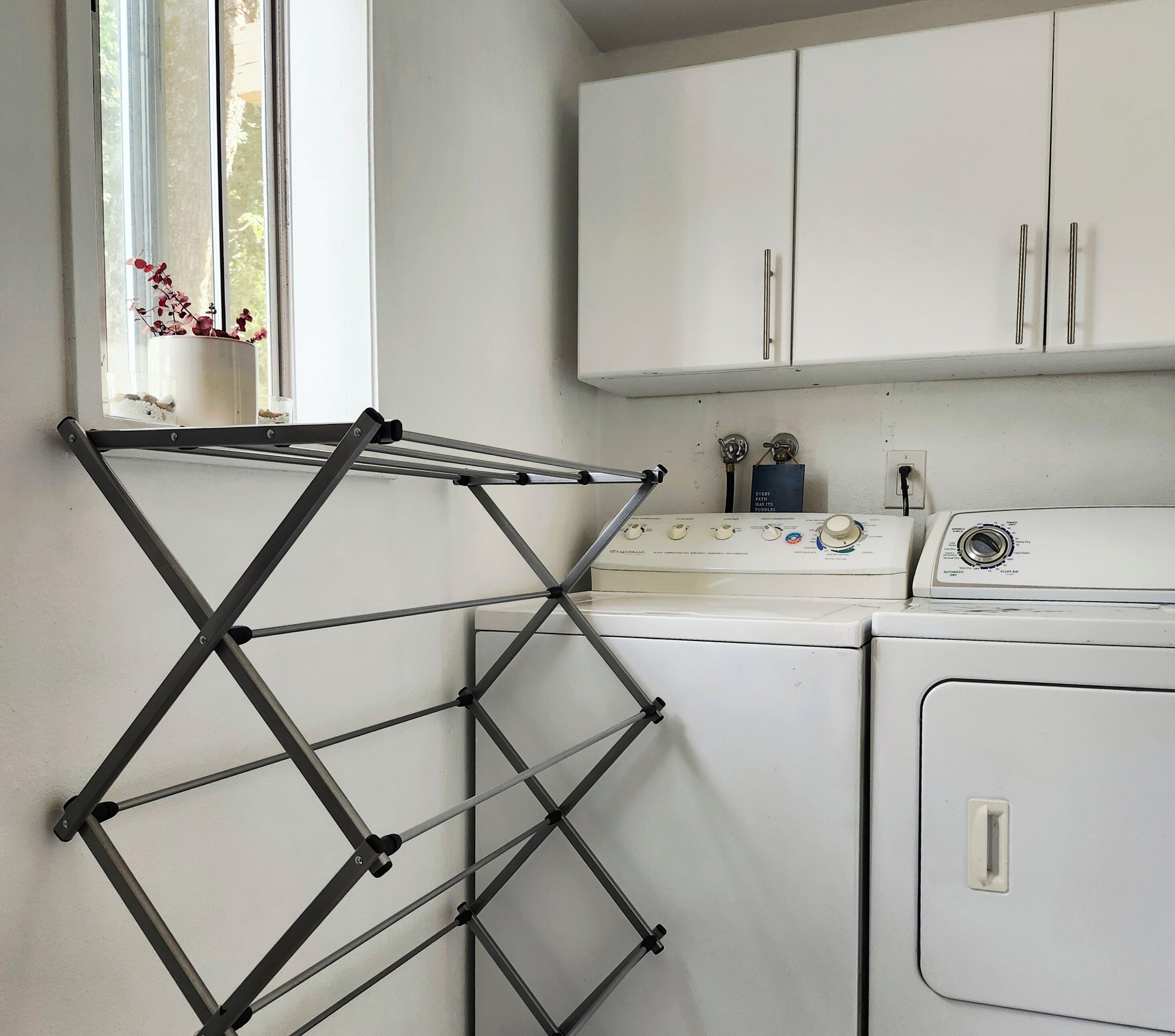 A laundry area with a drying rack, washing machine, and dryer.