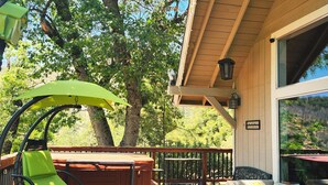 Eine Holzterrasse mit einer Hängematte, einem gepolsterten Stuhl und einer Couch.