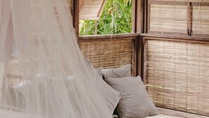A room with a bed covered by a mosquito net, wooden walls, and a window with a view of greenery. - Igapeba Moreré (Cairu)