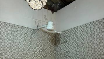 Un baño con paredes de mosaico, zona de ducha y un lavamanos blanco.