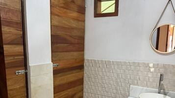 Un baño con puertas de madera, un lavamanos blanco, un espejo y una pared con textura.