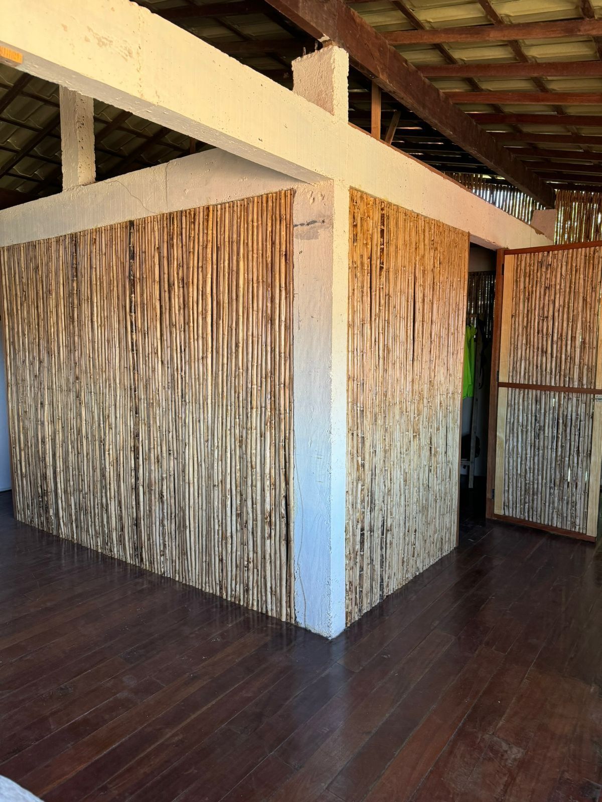 Una habitación con piso de madera, pared blanca y panel de bambú.