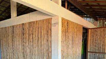 Una habitación con piso de madera, pared blanca y panel de bambú.