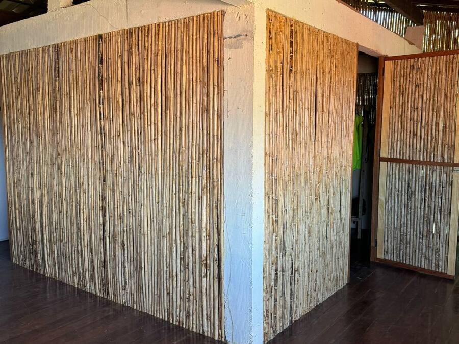 Una habitación con piso de madera, pared blanca y panel de bambú.