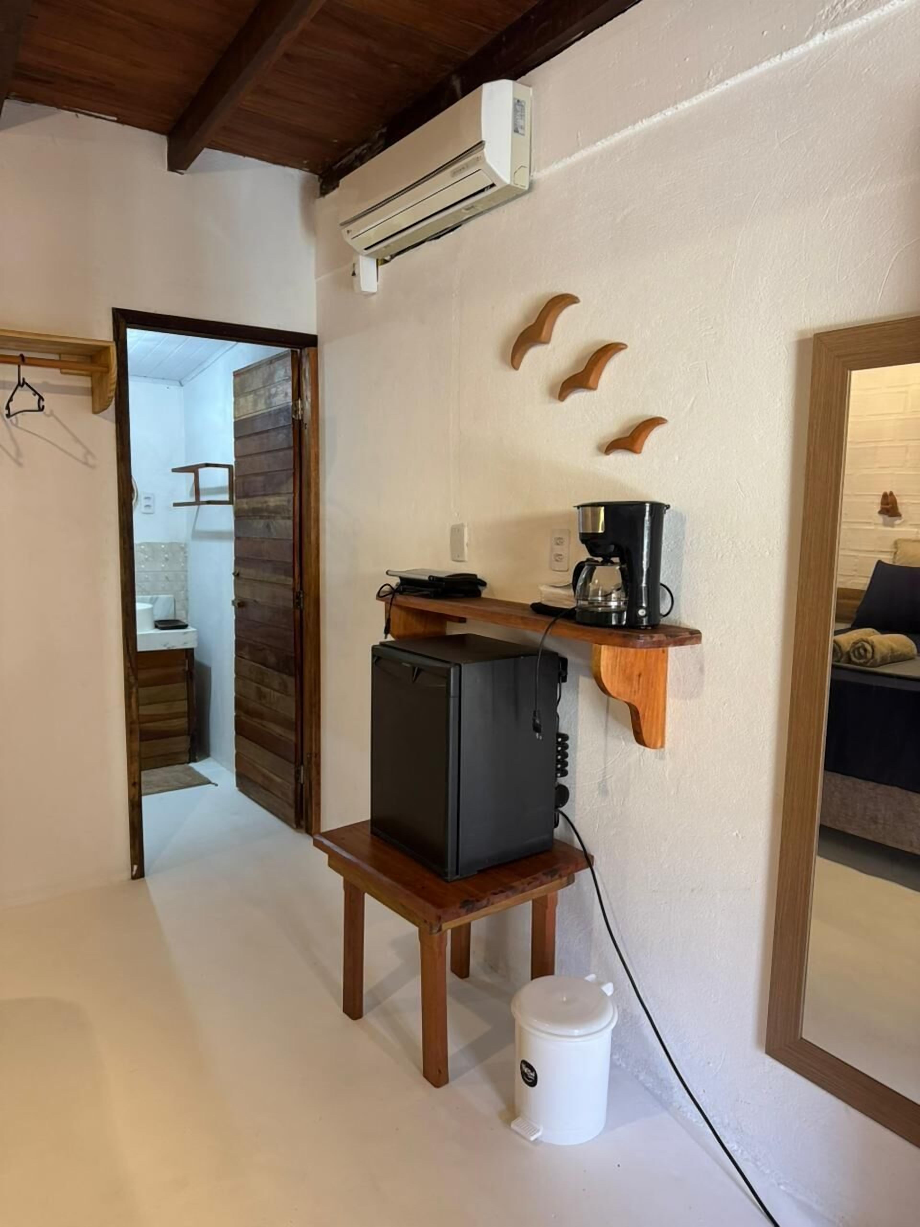 Uma cozinha compacta com geladeira, cafeteira e prateleiras de madeira.
