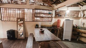 A rustic kitchen with wooden benches, a large table, and a refrigerator. - Igapeba Moreré (Cairu)