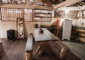 Uma cozinha rústica com bancos de madeira, uma mesa grande e uma geladeira.