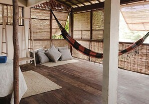 A hammock bed in a room with wooden flooring and a thatched roof. - Igapeba Moreré (Cairu)