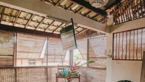 A room with a wooden table, chairs, and a woven mat. There is a large window with a view outside. - Igapeba Moreré (Cairu)