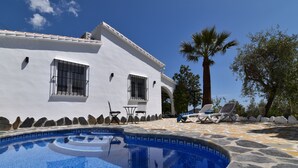 A white building with a swimming pool, stone tiles, and outdoor furniture. - Finca El Corinto. An enchanted place. (Cómpeta)
