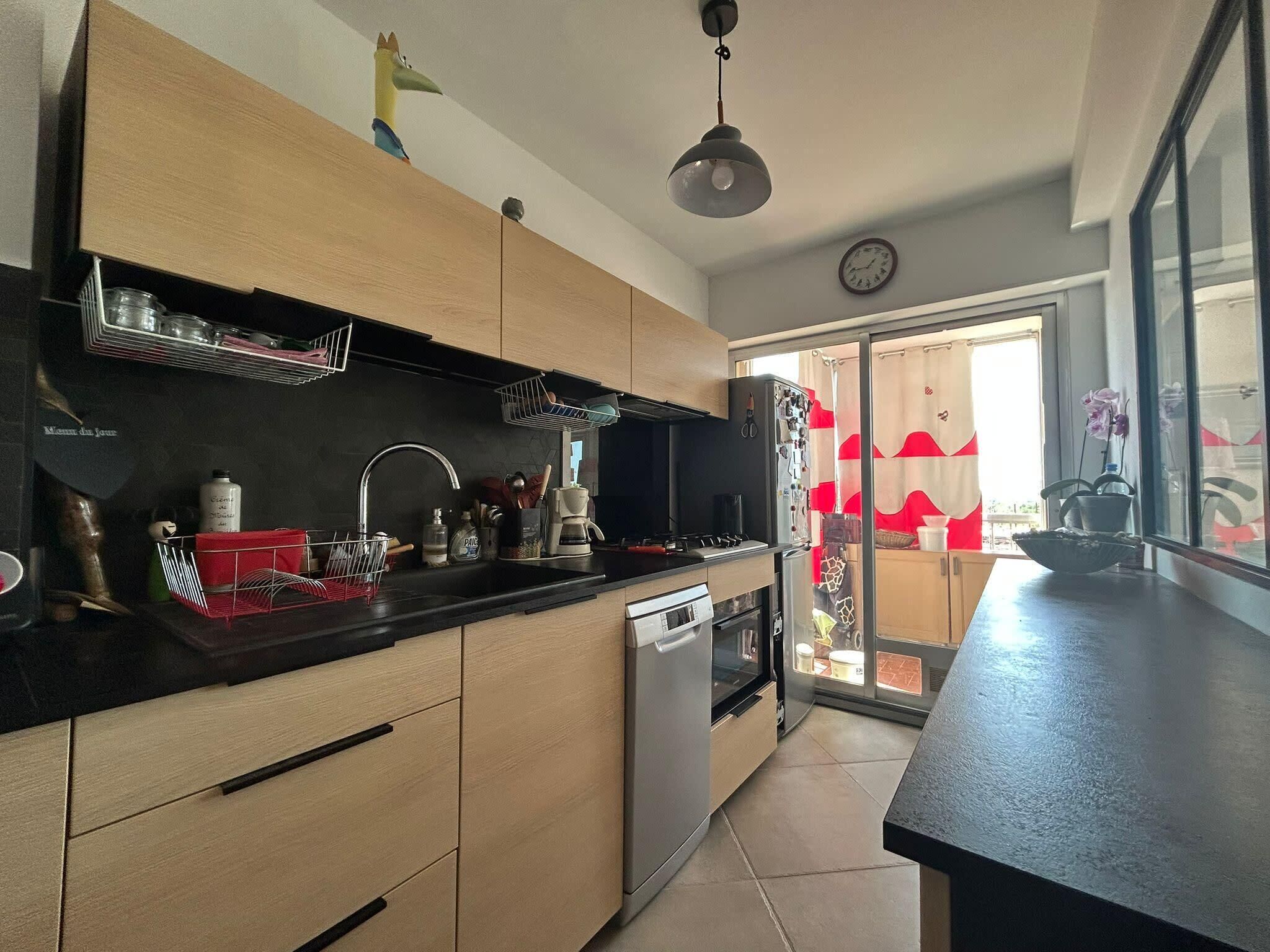 Eine moderne Küche mit Holzschränken, einem Edelstahlkühlschrank, einer Spüle und einer Kaffeemaschine.