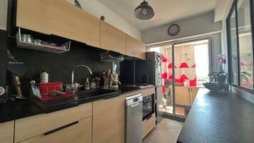 Eine moderne Küche mit Holzschränken, einem Edelstahlkühlschrank, einer Spüle und einer Kaffeemaschine.