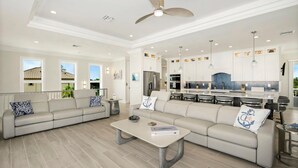 A spacious living room with a large sofa, a coffee table, and a ceiling fan. - Anchors Down (Fort Myers Beach)