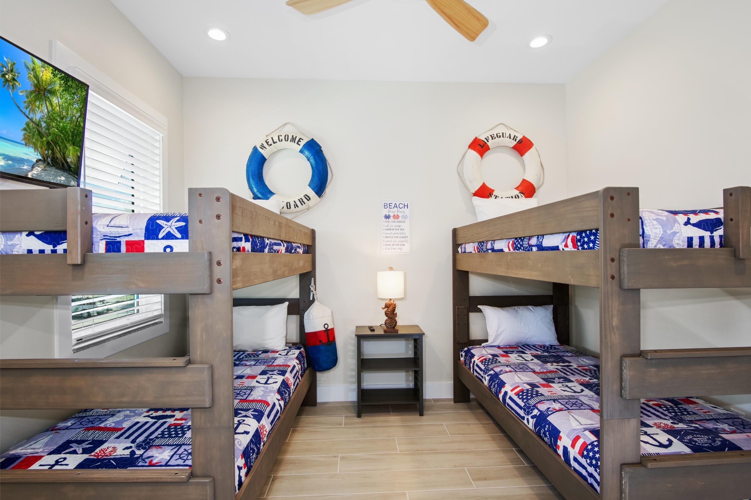 A room with bunk beds, a small table with a lamp, and life-saving rings on the wall.