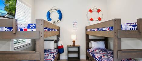 A room with bunk beds, a small table with a lamp, and life-saving rings on the wall.