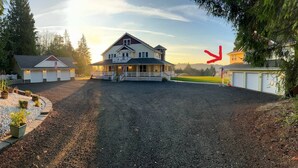 Uma casa de dois andares com varanda frontal, entrada por uma calçada e gramado bem cuidado.
