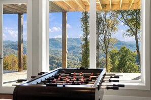 A foosball table in a room with large windows overlooking a mountainous landscape.