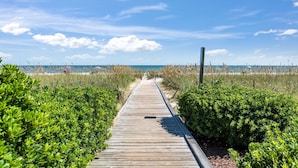 Una passerella di legno che conduce a una spiaggia sotto cieli sereni.