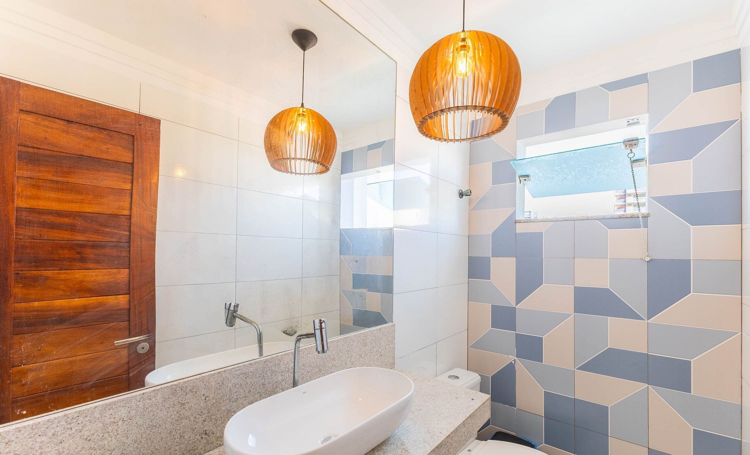 Ein modernes Badezimmer mit Holztür, einer freistehenden Badewanne, einem Waschtisch mit Spiegel und zwei Pendelleuchten.