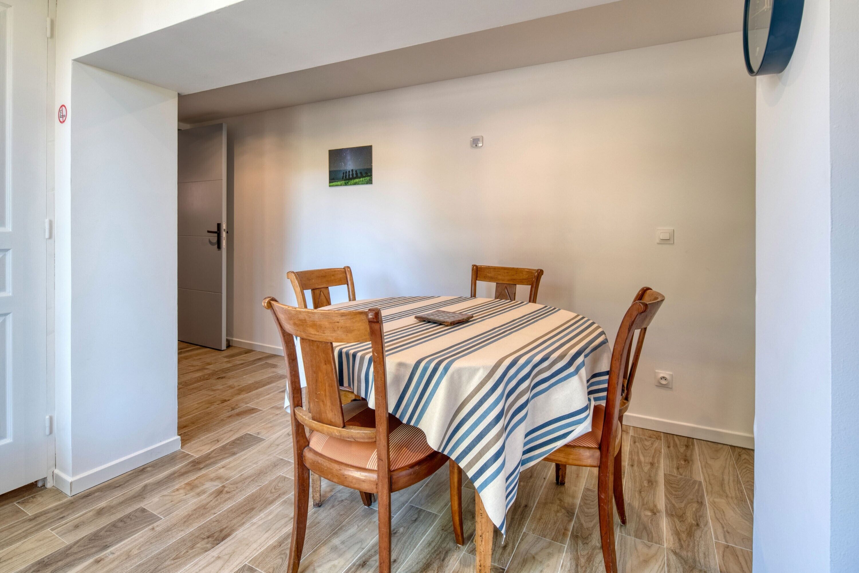 Un comedor con una mesa, sillas y mantel a rayas.