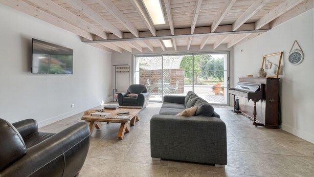 A modern living room with a sofa, a coffee table, a piano, and a television.