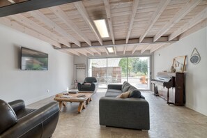 A modern living room with a sofa, a coffee table, a piano, and a television. - Guesthouse 'Domaine En Castanet' with Shared Pool, Private Garden and Wi-Fi (Caraman)