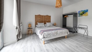 A bedroom with a bed, a hanging light fixture, a wardrobe, and a painting on the wall.