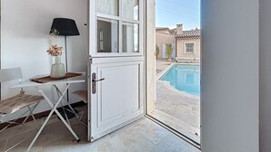 Une chambre avec vue sur une piscine, une porte blanche, une petite table avec une lampe et une chaise.