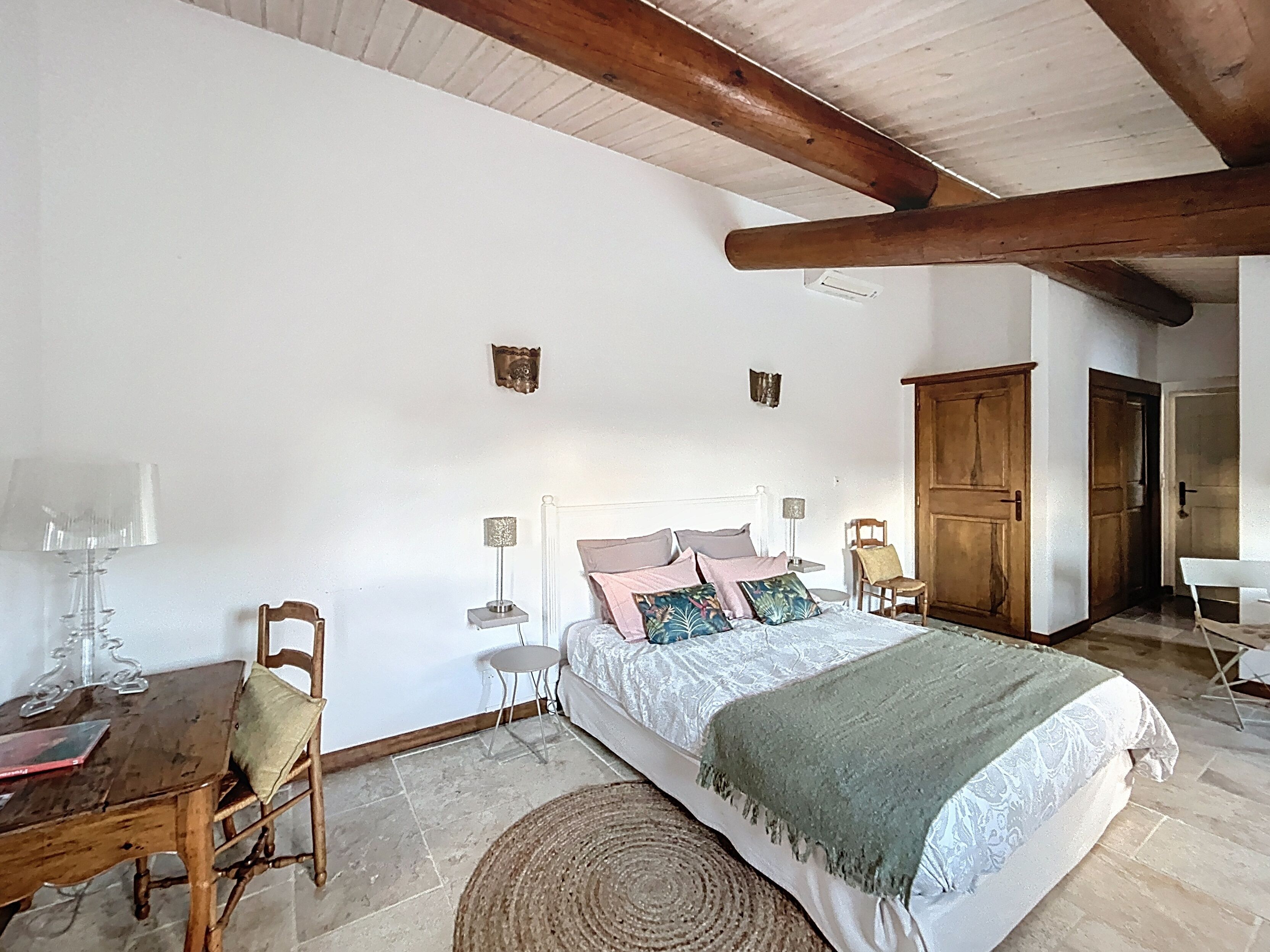 Een slaapkamer met een bed, nachtkastjes, een stoel, een lamp en een houten garderobe.
