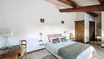 Een slaapkamer met een bed, nachtkastjes, een stoel, een lamp en een houten garderobe.