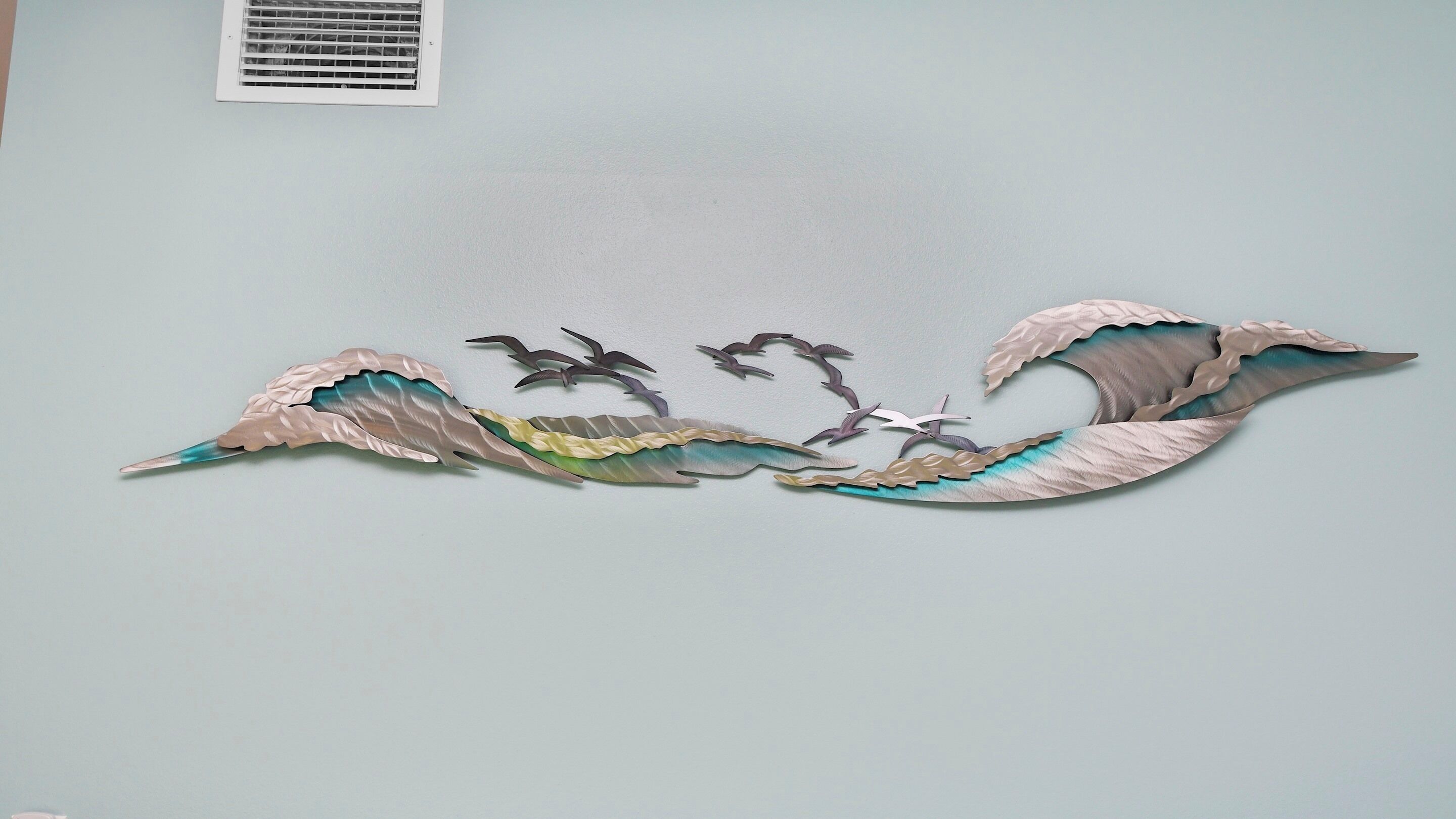 Un élément décoratif à fixer au mur, orné d’un motif ondulé et de motifs d’oiseaux.