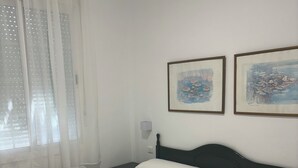 A hotel room with two beds, white bedding, a nightstand, a lamp, and two framed paintings on the wall. - ISLANTUR IPANEMA (Isla Cristina)