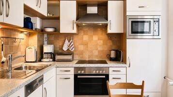 Una cocina moderna con armarios blancos, electrodomésticos de acero inoxidable, un horno Bosch y un microondas.