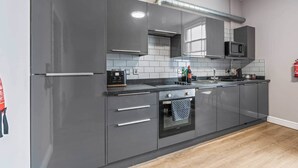 Eine moderne Küche mit grauen Schränken, einer Edelstahl-Dunstabzugshaube, einer Mikrowelle und einem Einbauofen.