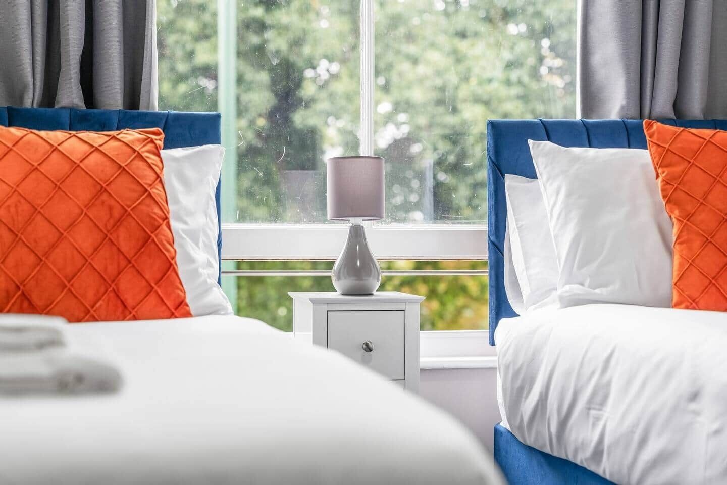 A hotel room with a bed, a nightstand, and a lamp.