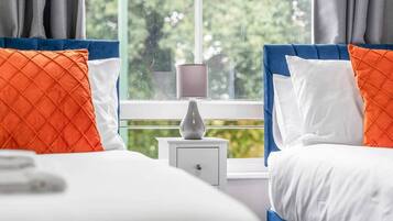 A hotel room with a bed, a nightstand, and a lamp.